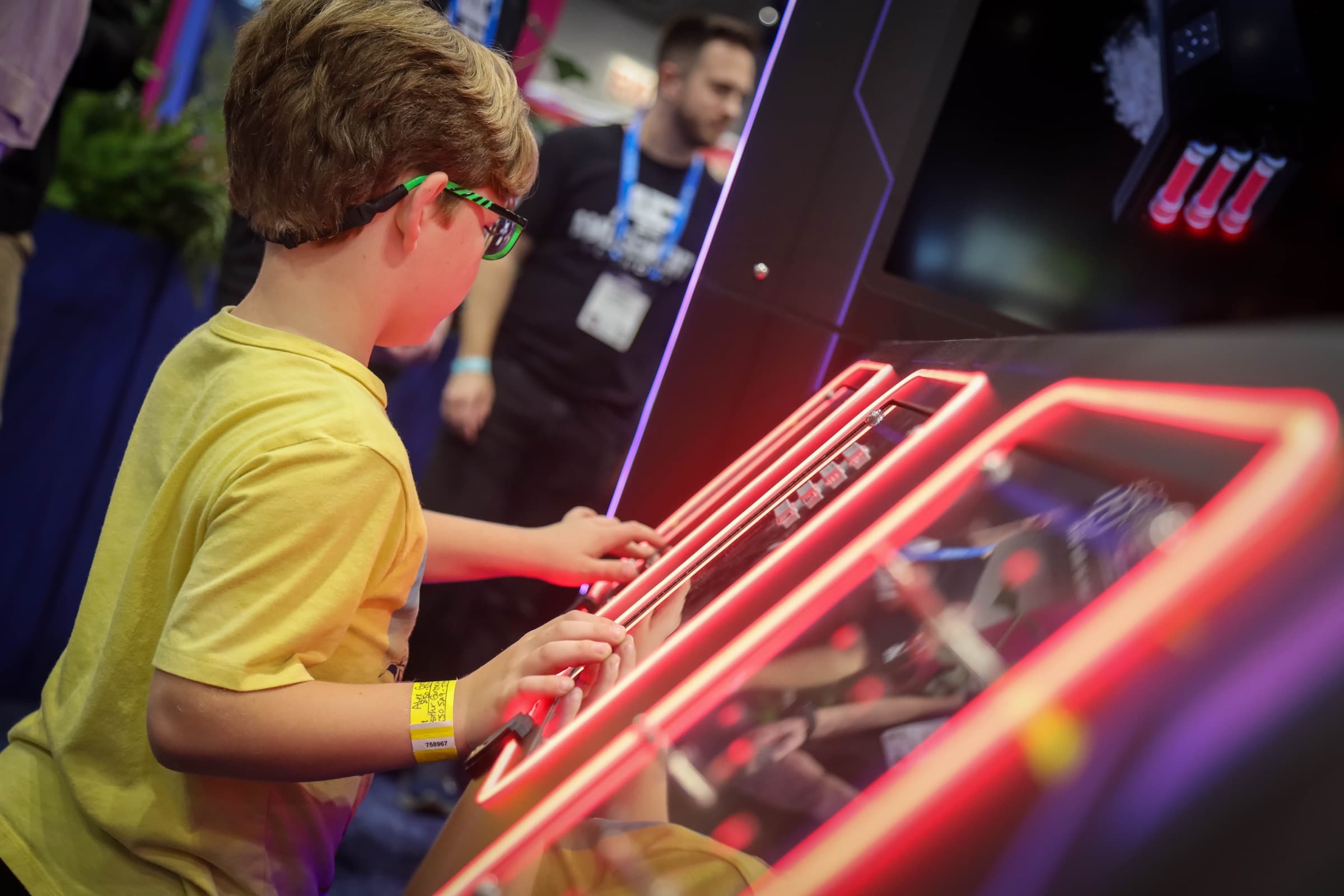 A young player working a neon-lit DETONATE puzzle panel